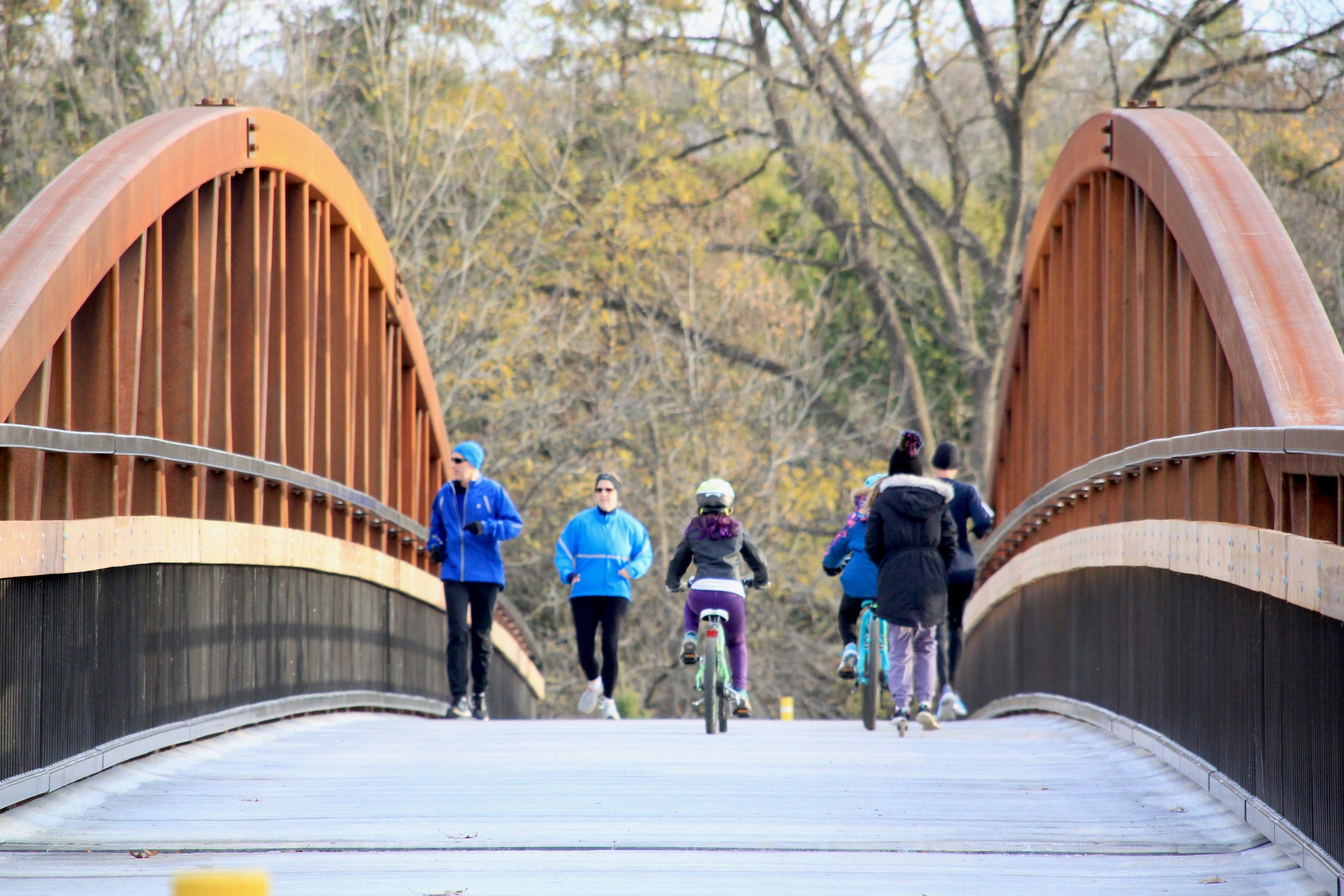 Four people jogging on bridge