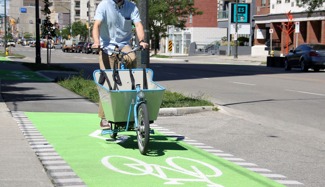 A person rides a cargo bike down a protected bike lane in London, Ontario. 