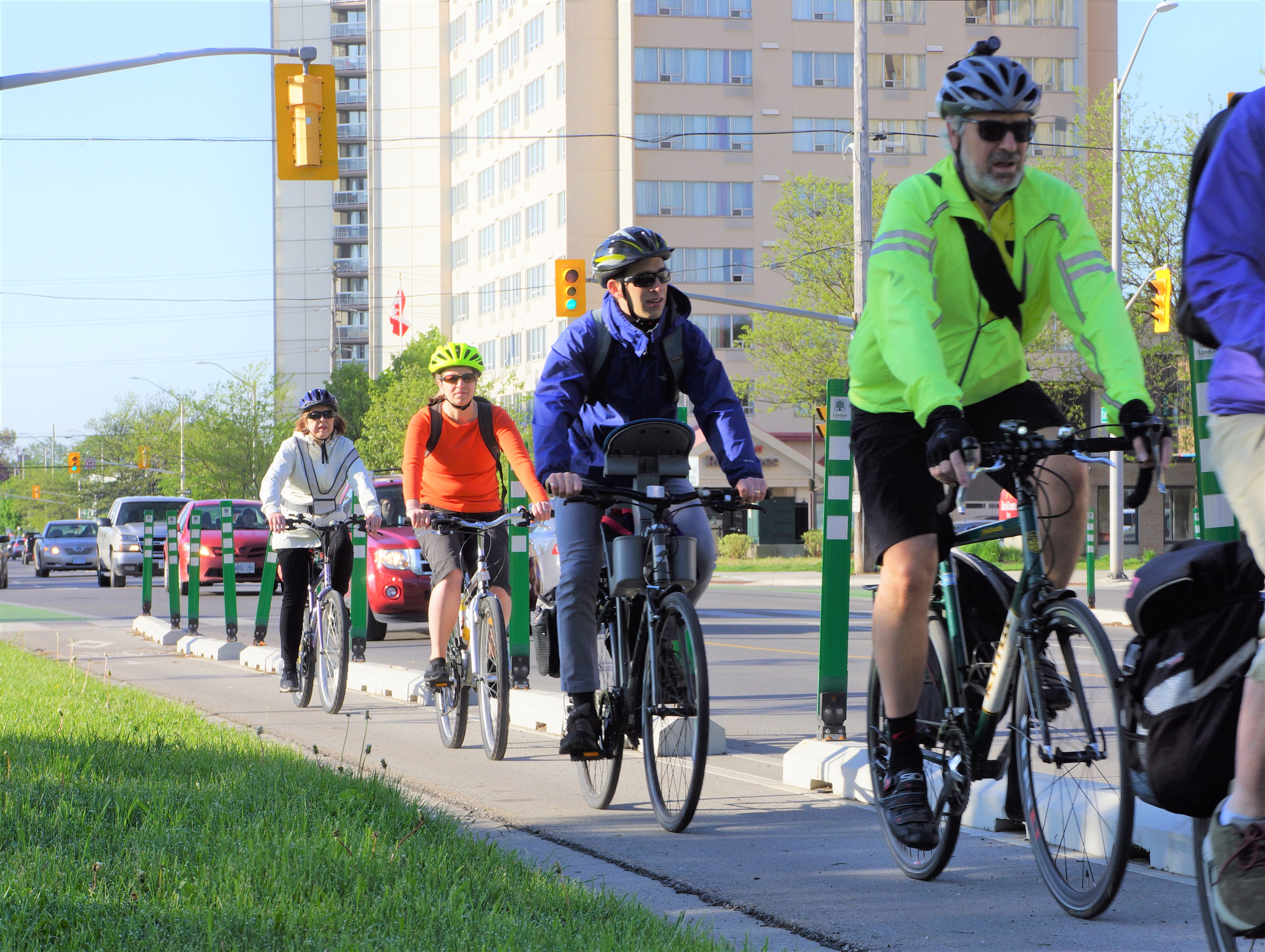 A group of people ride their bikes in a protected bike lane on Colborne Street downtown. 
