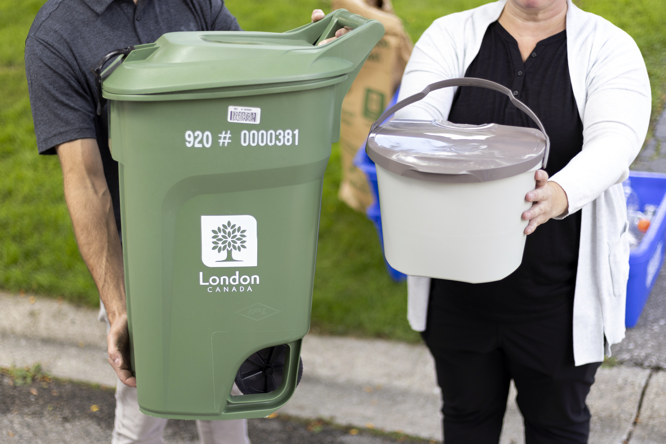 A Green Bin is held next to a Kitchen Catcher container. 