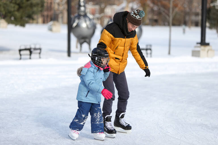 A father teaching helping his daughter skate
