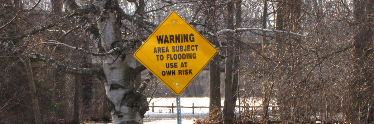 Yellow sign that says "Warning: area subject to flooding, use at own risk."