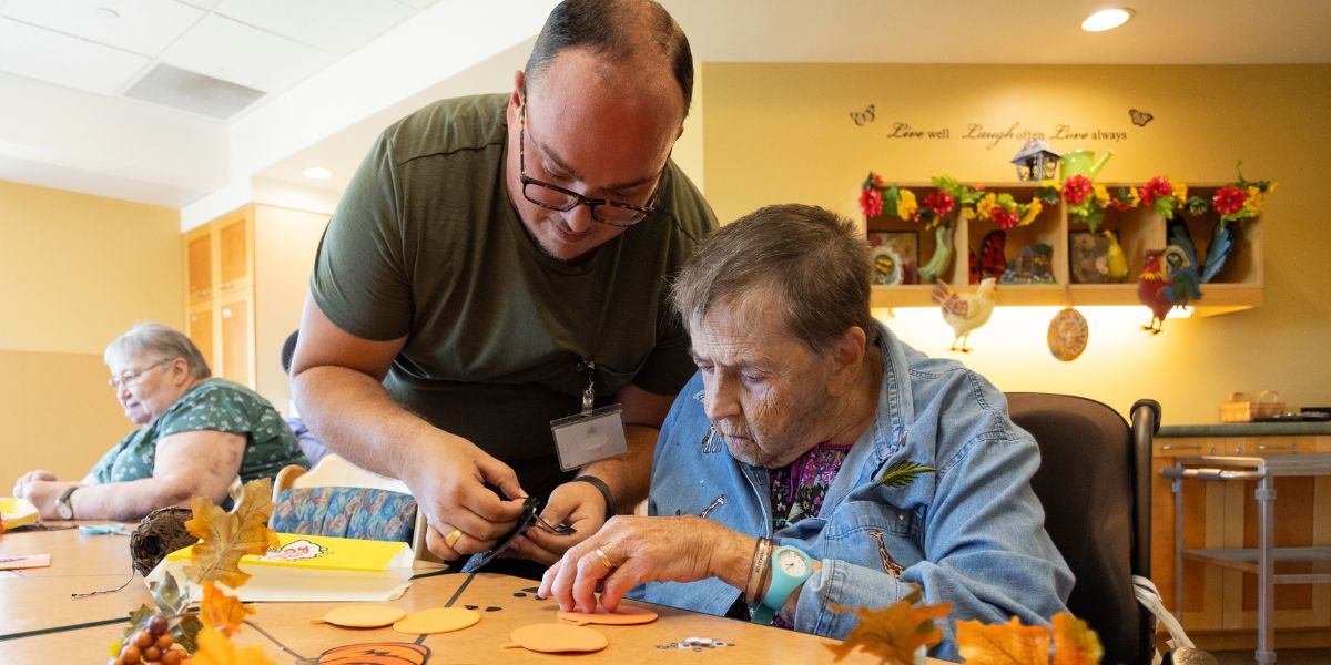 Dearness Home resident and worker participating in a fall craft activity.