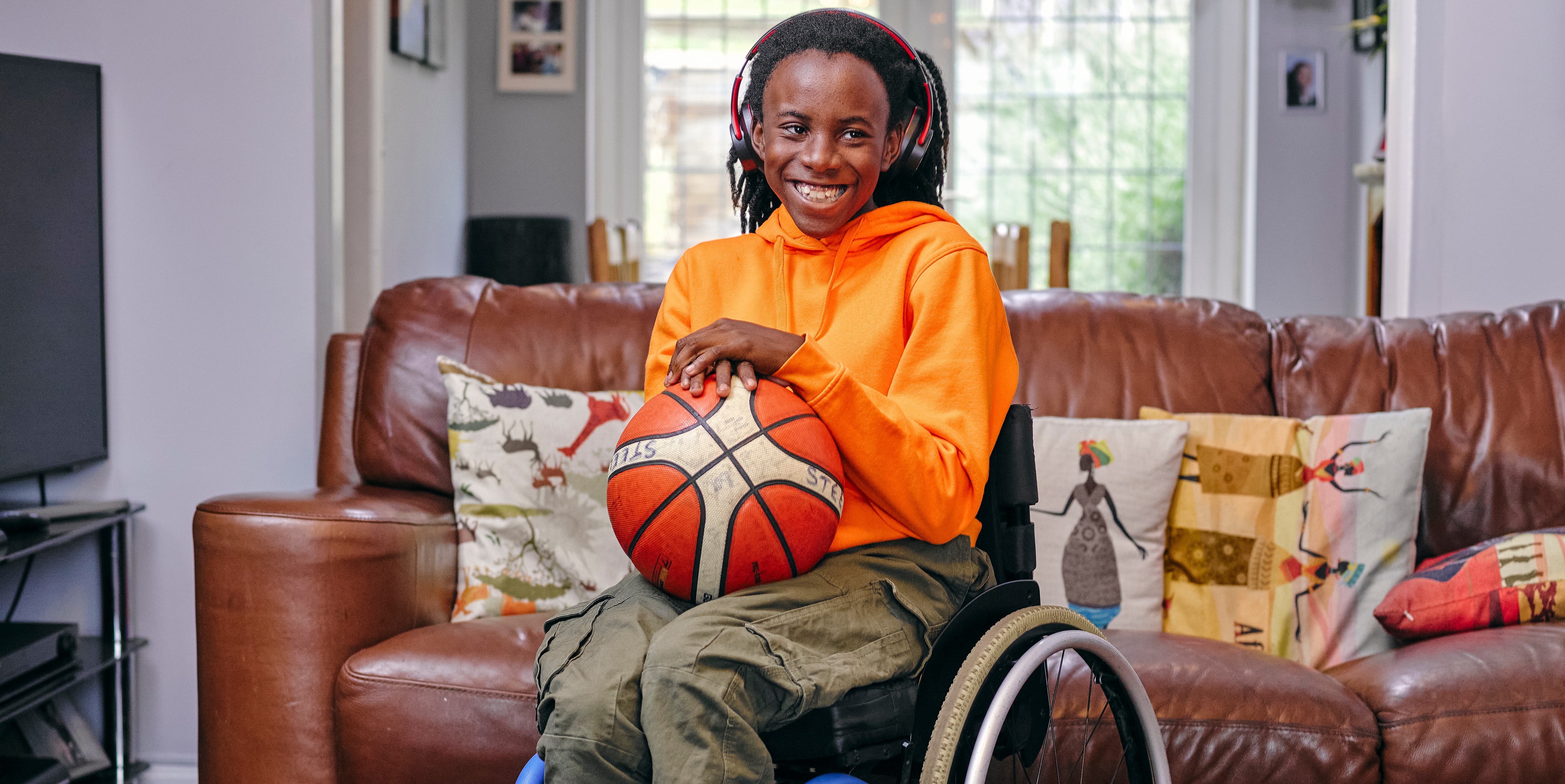 Girl in wheelchair smiling with basketball in her hands