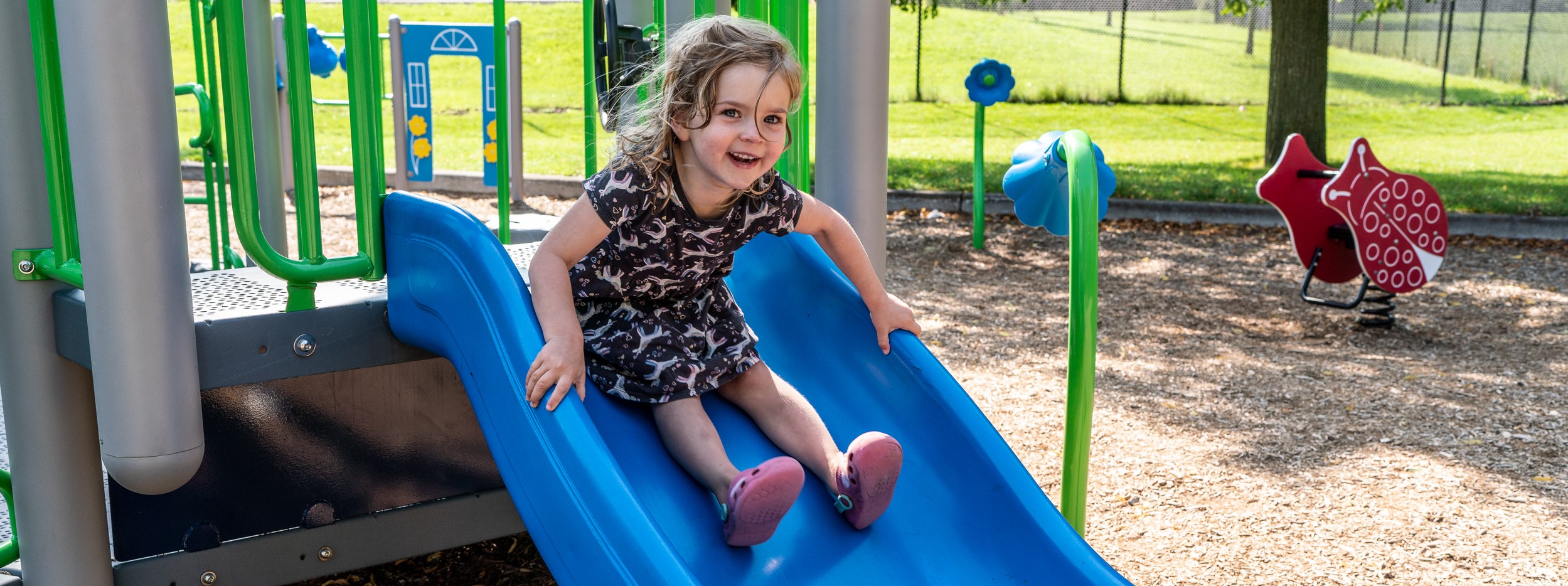 Girl riding down slide at local park