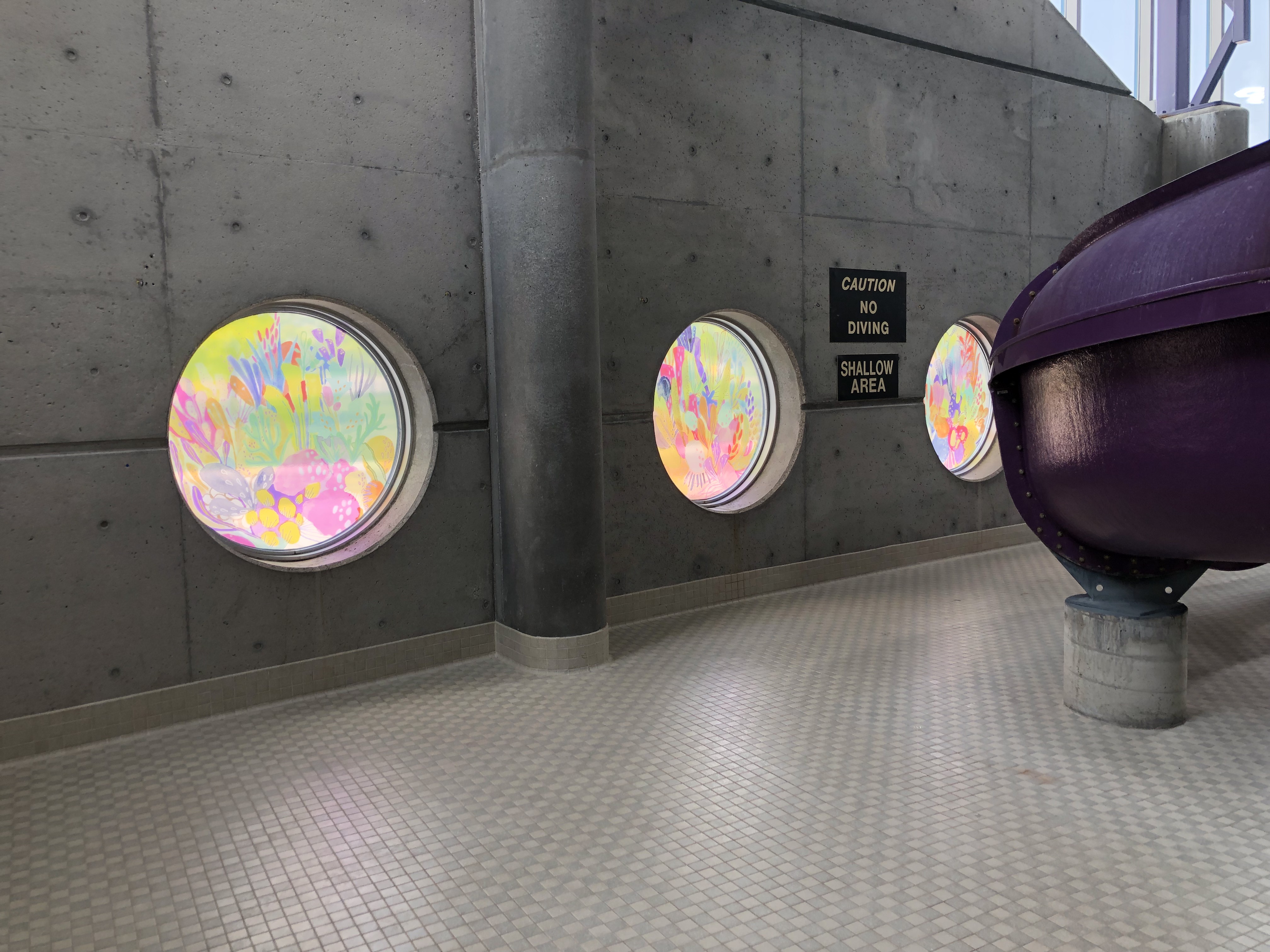 Coral reef murals in the circular windows at the South London Community Pool