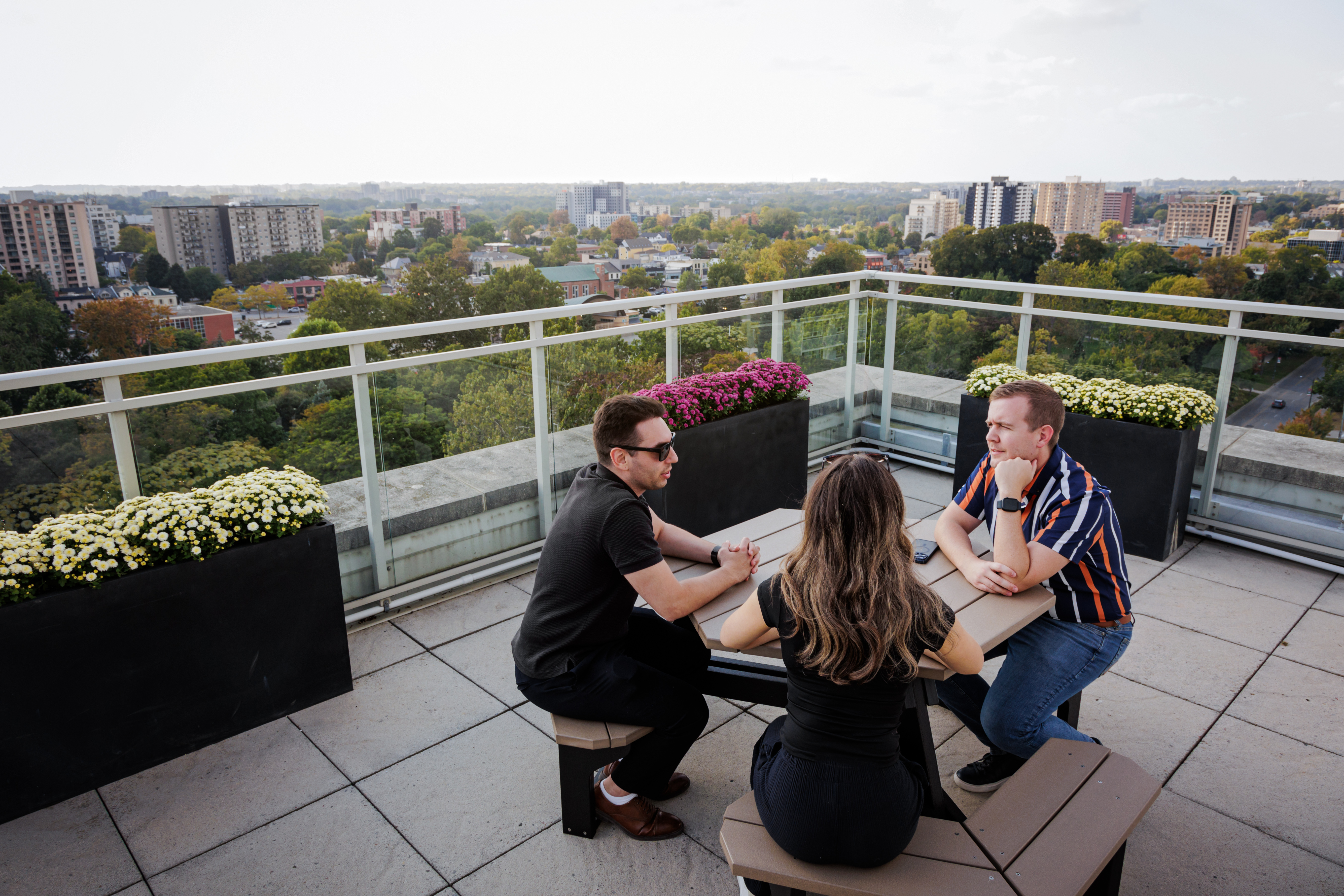 Three people sitting at a picnic table at City Hall's observation deck