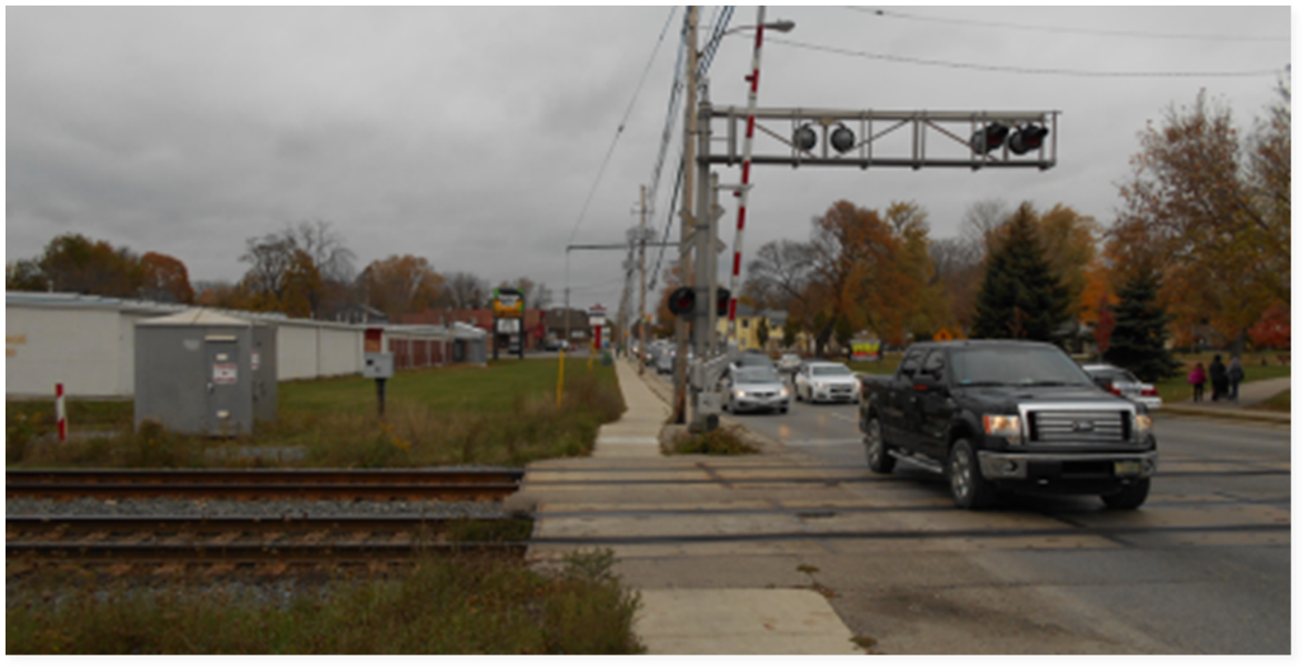 Traffic congestion at the Adelaide Street North rail crossing prior to construction of the underpass, where frequent train activity often caused delays and safety concerns for vehicles, cyclists, and pedestrians.