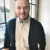 Man in sweater and button up smiling