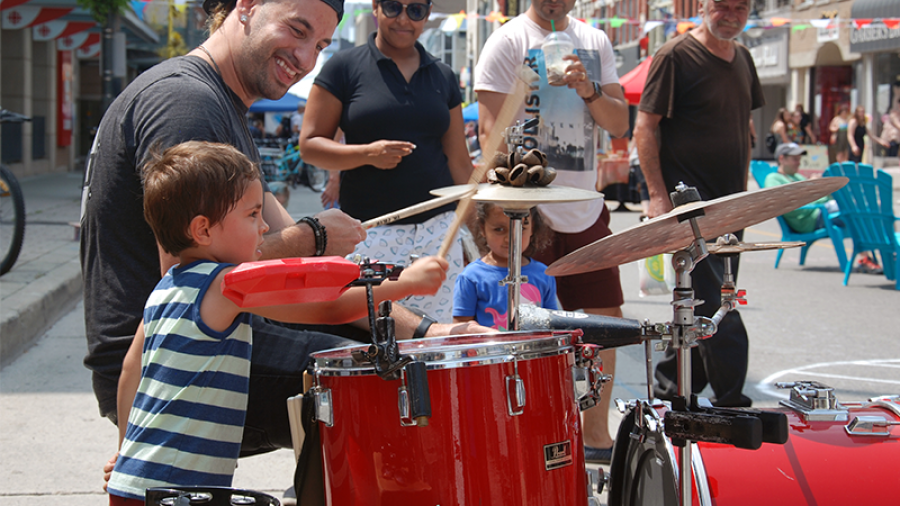 Man and boy playing drums while people watch
