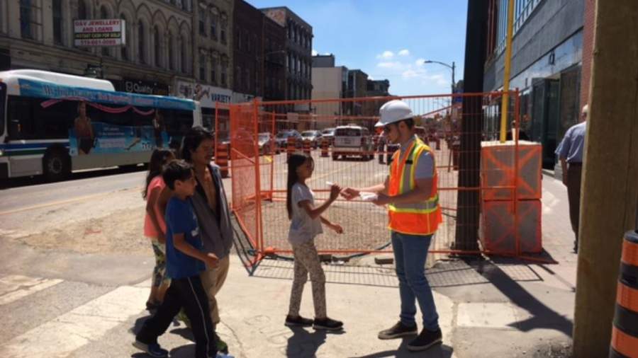 Construction crews speak to pedestrians walking past Dundas Place