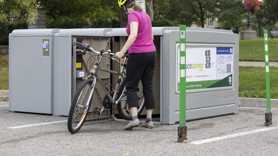 A woman places her bike into a secure bike locker outdoors downtown. 