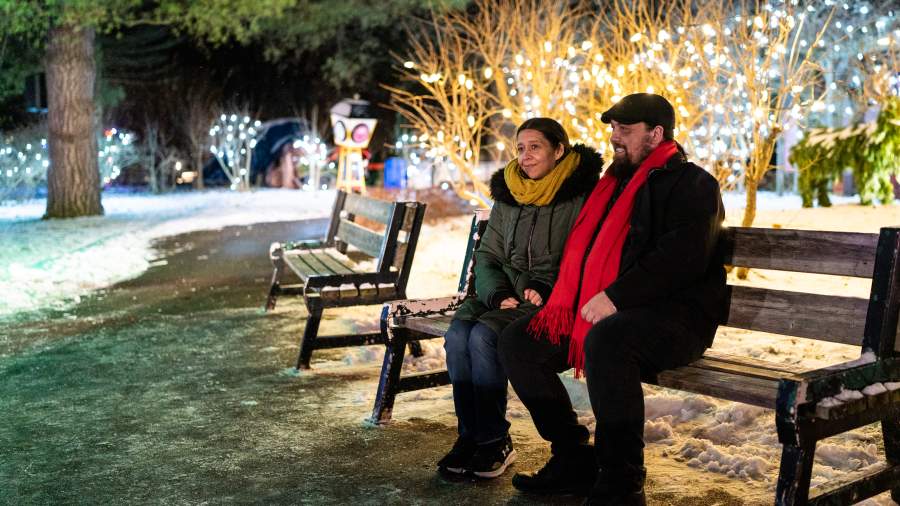 Two people sitting on a bench enjoying the holiday lights