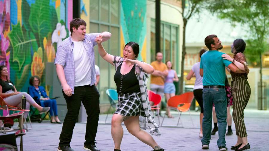 Two people dance together on Dundas Place in Market Lane